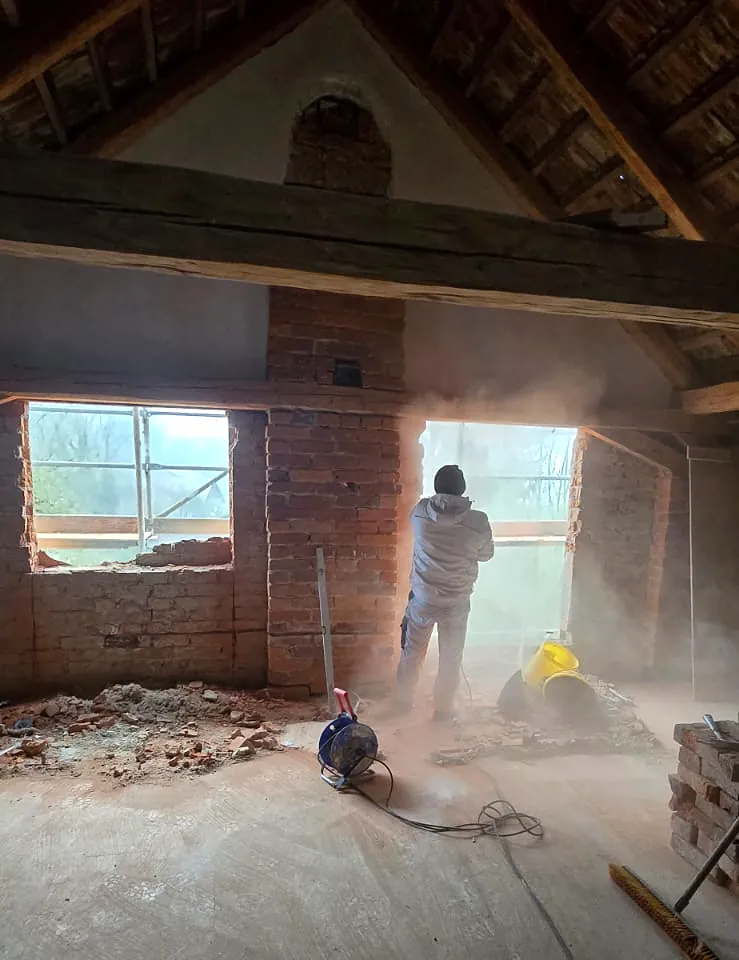Dachgeschoss im Rohbau mit Staub und Mauerdurchbruch